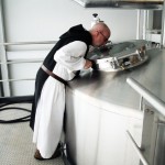 A trappist monk at the Spencer Brewery looks into a brew tank.