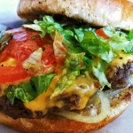 A large hamburger with tomatoes cheese and lettuce