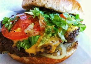 A large hamburger with tomatoes cheese and lettuce