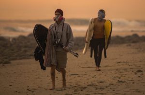 Surfers walk along the coastline wearing masks to keep smoke and ash out from the Thomas fire.
