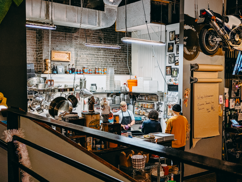 Looking into the bright kitchen, with pans hanging.